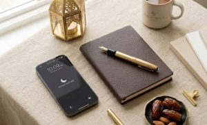 A neat workspace with a smartphone set to Do Not Disturb, a leather notebook, dates, and a traditional gold Ramadan lantern, symbolizing professional recovery during Eid.